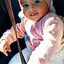 baby, child, headband, flower, pink_clothing, sweater, white_pants, car_seat, seatbelt, smiling, tongue_out, sunlight, cozy, cute, portrait, indoor, happy, infant, safe, closeup