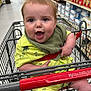 baby, child, shopping_cart, grocery_store, yellow_outfit, bib, smiling, happy, infant, retail, aisle, products, dinosaur_print, person, cute, indoor, cart_handle, clothing, footwear, socks