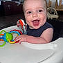James joined the competition — help win amazing prizes! baby, child, smiling, high_chair, toy, colorful, happy, indoor, face, hand, infant, person, cute, playful, furniture, room, expression, young, sitting, clothing
