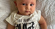 Lucius joined the competition — help win amazing prizes! arm, baby, casual, closeup, clothing, cute, expression, face, green_lenses, hand, head, indoor, infant, lying_down, person, portrait, skin, sunglasses, text_on_shirt, white_blanket
