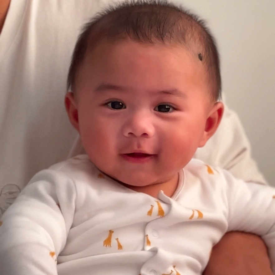 Deon is registered to the contest to win money with this photo: baby, casual, child, closeup, cute, face, giraffe_print, happy, human, indoor, infant, onesie, person, portrait, sitting, smiling, soft_lighting, supporting_arm, white_clothing, young_child