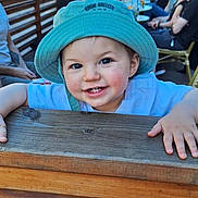 Léo a rejoint le concours — aidez-le/la à gagner de superbes lots ! toddler, child, hat, smile, outdoor, wood, fence, people, street, cafe, daylight, blue_sky, building, table, group, happy, casual, portrait, person, urban