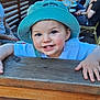toddler, child, hat, smile, outdoor, wood, fence, people, street, cafe, daylight, blue_sky, building, table, group, happy, casual, portrait, person, urban