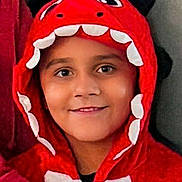 Austin is registered to the contest to win money with this photo: child, costume, dinosaur, hood, red, smile, face, portrait, person, cute, clothing, kid, happy, young, fashion, fun, indoor, headwear, expression, playful