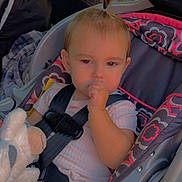 Charlotte is registered to the contest to win money with this photo: toddler, child, car_seat, seatbelt, toy, stuffed_animal, thumb_in_mouth, pony_tail, car_interior, window, sunlight, clothing, patterned_pants, pink_shirt, safety, baby, cute, portrait, indoor, seat