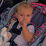 toddler, child, car_seat, seatbelt, toy, stuffed_animal, thumb_in_mouth, pony_tail, car_interior, window, sunlight, clothing, patterned_pants, pink_shirt, safety, baby, cute, portrait, indoor, seat