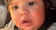 Payton joined the competition — help win amazing prizes! baby, infant, face, close_up, bottle, car_seat, seatbelt, drool, curious, child, young, person, clothing, hair, skin, expression, indoors, light, portrait, warm_light