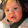 baby, infant, face, close_up, bottle, car_seat, seatbelt, drool, curious, child, young, person, clothing, hair, skin, expression, indoors, light, portrait, warm_light