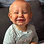 Alezio participe au concours pour gagner de l'argent avec cette photo : baby, smiling, drool, batman, shirt, toy, hands, closeup, face, child, happy, indoor, couch, blurry_background, infant, cute, playing, person, portrait, light