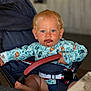 toddler, child, stroller, blue_eyes, chocolate_mess, clothing, seatbelt, hand, foot, face, hair, indoor, table, fabric, person, sitting, cute, infant, baby, expression