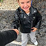 Inaya a rejoint le concours — aidez-le/la à gagner de superbes lots ! child, smiling, holding_hands, blue_bow, leather_jacket, jeans, white_shoes, outdoor, gravel, sidewalk, person, happy, portrait, fashion, casual, nature, greenery, accessory, cute, young