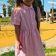Inaya participe au concours pour gagner de l'argent avec cette photo : child, girl, pink_dress, tree, playground, sunlight, grass, shoes, smile, long_hair, outdoor, daylight, nature, park, rope_climbing_structure, happy, casual, person, young, shadow