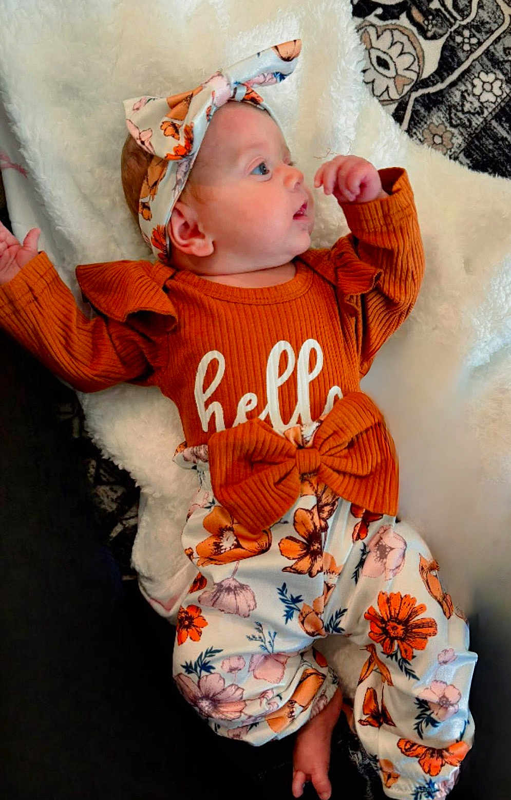 Layla joined the competition — help win amazing prizes! baby, infant, headband, orange_clothing, floral_pattern, blanket, cute, lying_down, child, soft_texture, fabric, portrait, small_hand, face, apparel, patterned_pants, white_blanket, colorful, adorable, resting