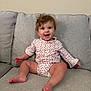 Camden joined the competition — help win amazing prizes! baby, child, smiling, couch, curly_hair, happy, sitting, indoors, clothing, pattern, face, person, infant, cute, cheerful, light_skin, home, furniture, young_child, portrait