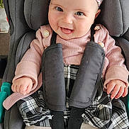 Sofia a rejoint le concours — aidez-le/la à gagner de superbes lots ! baby, child, car_seat, headband, pink_sweater, plaid_skirt, white_tights, smiling, happy, cute, infant, sitting, indoors, safety_harness, clothing, person, face, portrait, young_child, accessory