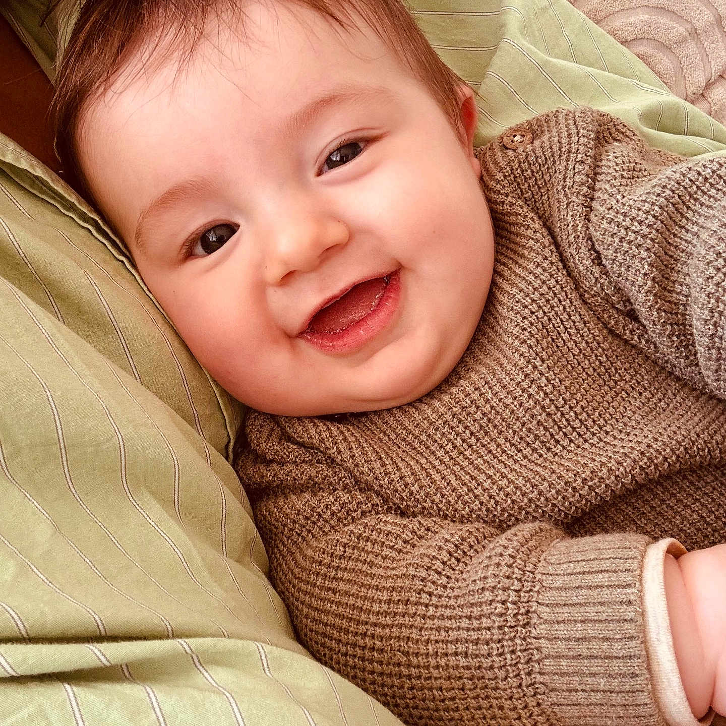 Isaac a rejoint le concours — aidez-le/la à gagner de superbes lots ! baby, child, smiling, face, knitted_sweater, cozy, cushion, green, beige, portrait, happy, cute, infant, closeup, warm, indoor, soft_texture, person, toddler, relaxed