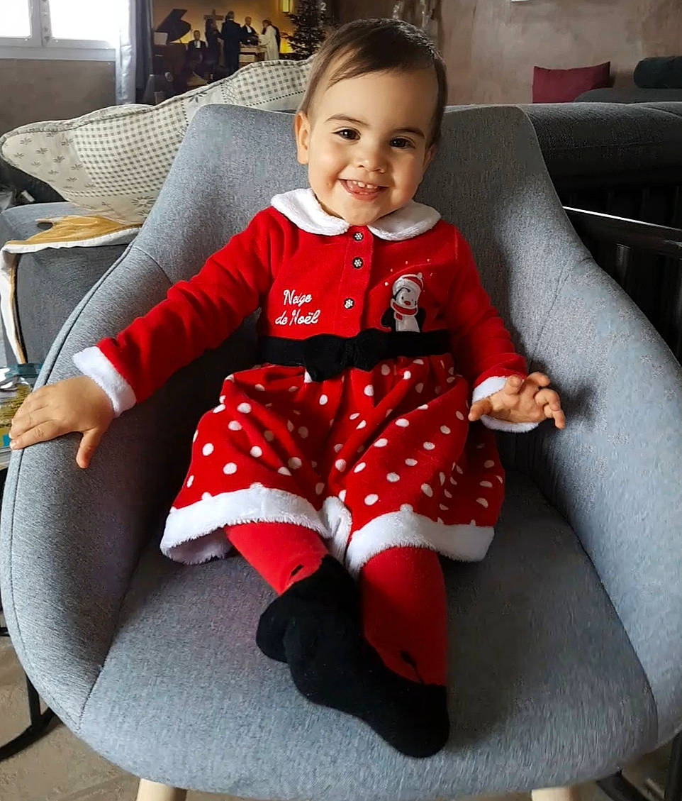 Emie participe au concours pour gagner de l'argent avec cette photo : baby, baby_toddler_clothing, black, car_seat, comfort, couch, dress, face, happy, human_body, human_leg, joy, knee, lap, pattern, person, sitting, sleeve, smile, sock