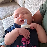 Luca joined the competition — help win amazing prizes! baby, pacifier, arm, couch, pillow, clothing, person, sleepy, indoor, fabric, hand, face, infant, sitting, relaxing, comfort, casual, adult, wristwatch, text