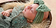 Nina participe au concours pour gagner de l'argent avec cette photo : baby, sleeping, infant, green_headwrap, lace_dress, basket, soft_texture, cozy, peaceful, cute, newborn, portrait, closeup, hands, head, skin, resting, delicate, fabric, fuzzy