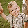 blonde_hair, blue_eyes, boy, casual_clothing, child, daylight, family, grass, happy, holding_hands, nature, outdoor, people, polka_dot_shirt, portrait, smiling, summer, suspenders, tattoo, toddler