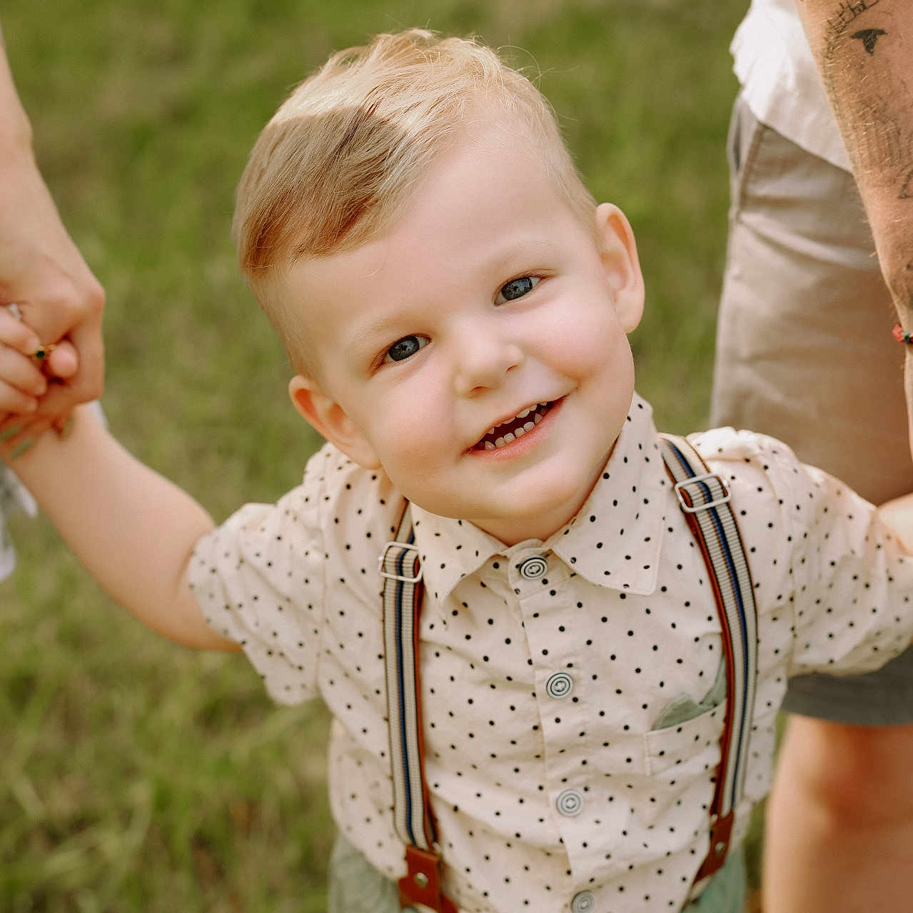 Ikaris is registered to the contest to win money with this photo: blonde_hair, blue_eyes, boy, casual_clothing, child, daylight, family, grass, happy, holding_hands, nature, outdoor, people, polka_dot_shirt, portrait, smiling, summer, suspenders, tattoo, toddler