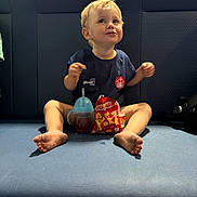 Dylan is registered to the contest to win money with this photo: barefoot, bench, blue_cushion, casual_clothing, child, cute, food, fun, happy, indoor, messy_eating, portrait, relaxed, seat, short_hair, sippy_cup, smiling, snack, toddler, young_child