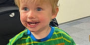 Dylan is registered to the contest to win money with this photo: background, blonde_hair, casual, child, chocolate, counter, cute, face, furniture, happy, indoor, messy_face, person, playful, room, shelf, sitting, smiling, striped_clothing, toddler