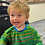 Dylan is registered to the contest to win money with this photo: child, toddler, indoor, smiling, blonde_hair, striped_clothing, chocolate, face, happy, person, sitting, furniture, room, shelf, counter, casual, background, playful, cute, messy_face