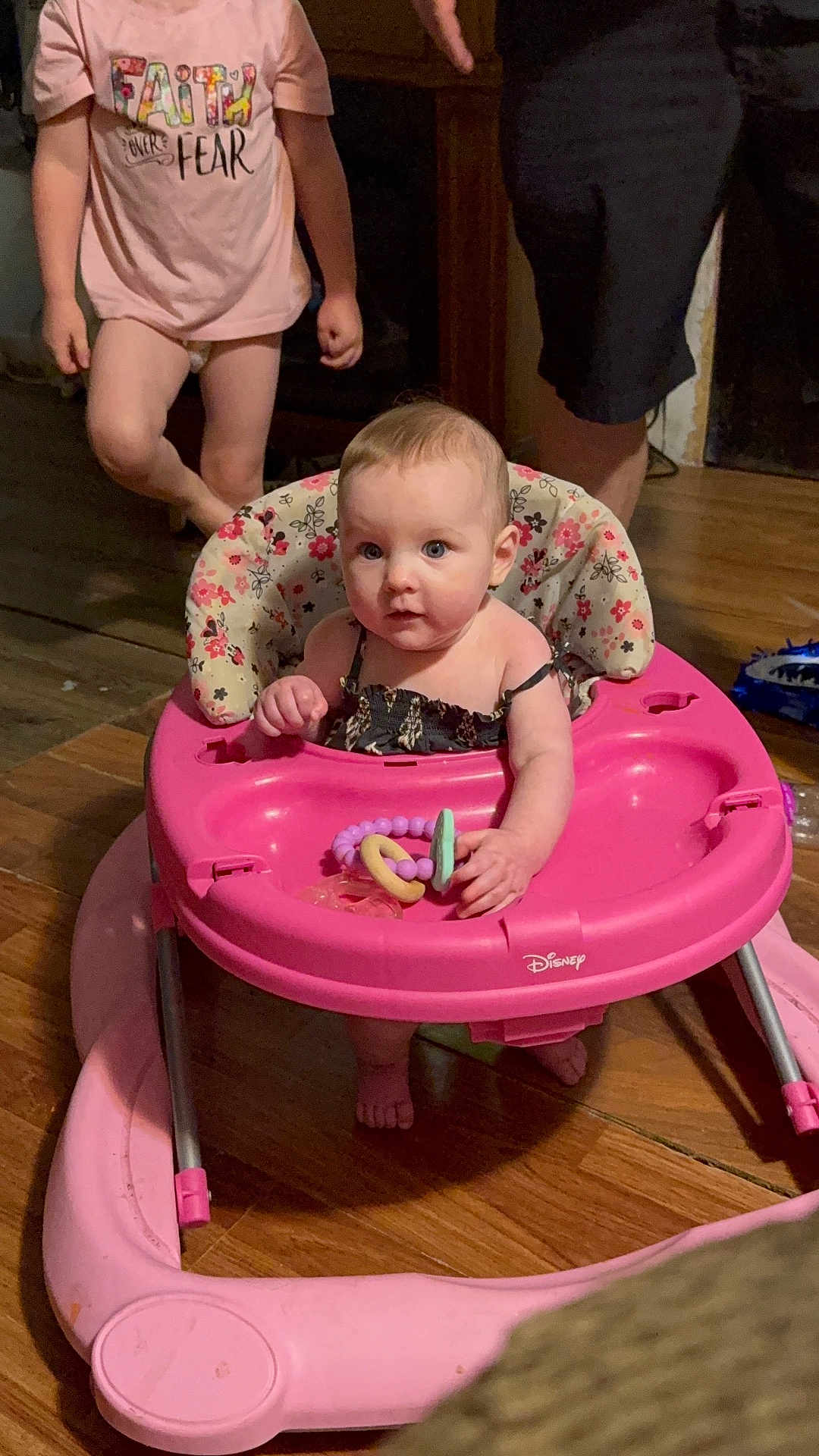 Aubrey is registered to the contest to win money with this photo: baby, toddler, walker, toy, pink, floor, wooden_floor, clothing, child, indoor, person, play, cute, sitting, hand, foot, shirt, text_on_clothing, family, home