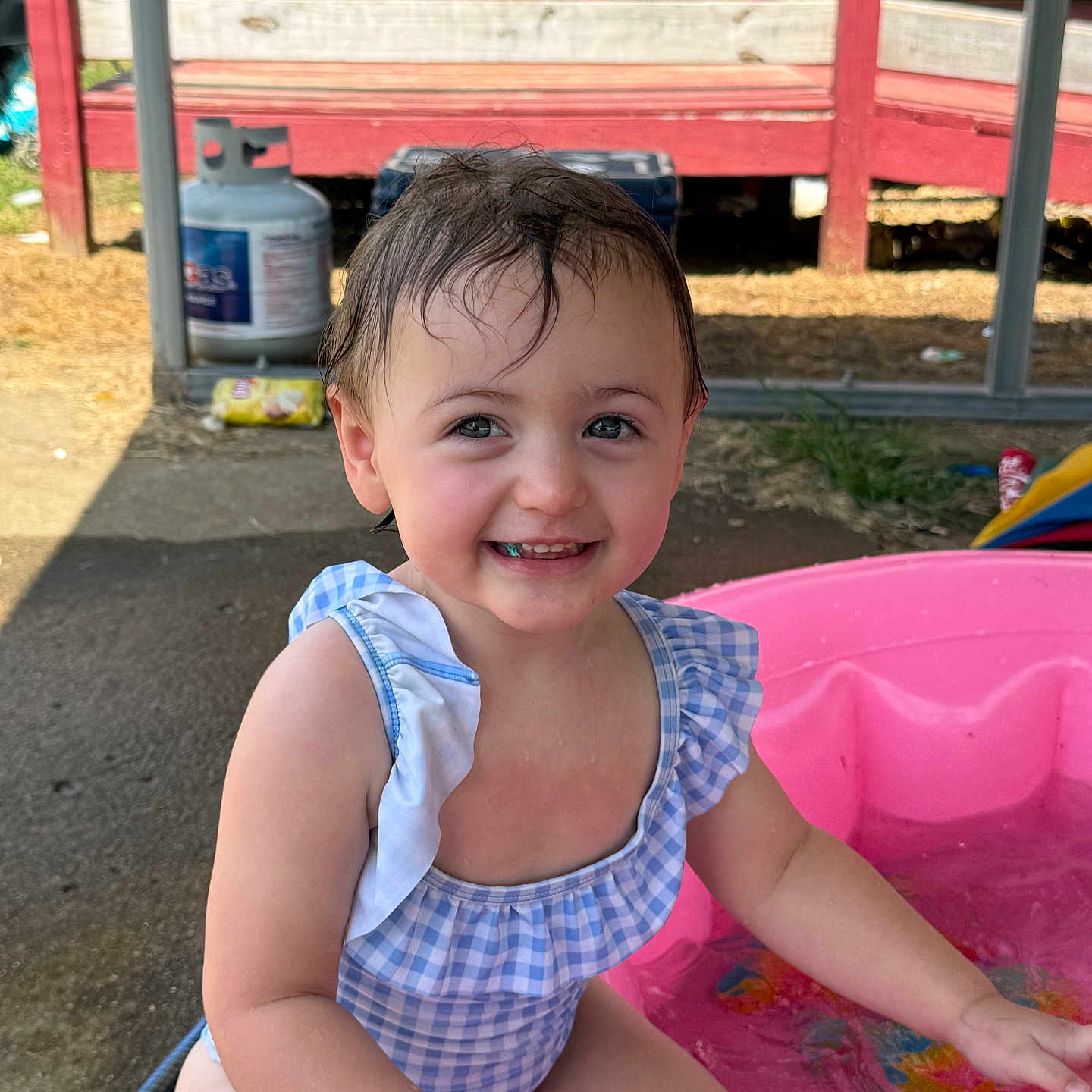 Freya joined the competition — help win amazing prizes! blue, child, concrete, cute, happy, outdoor, pink_pool, play, pool, porch, propane_tank, smiling, splashing, summer, sunlight, swimsuit, toddler, water, wet_hair, white