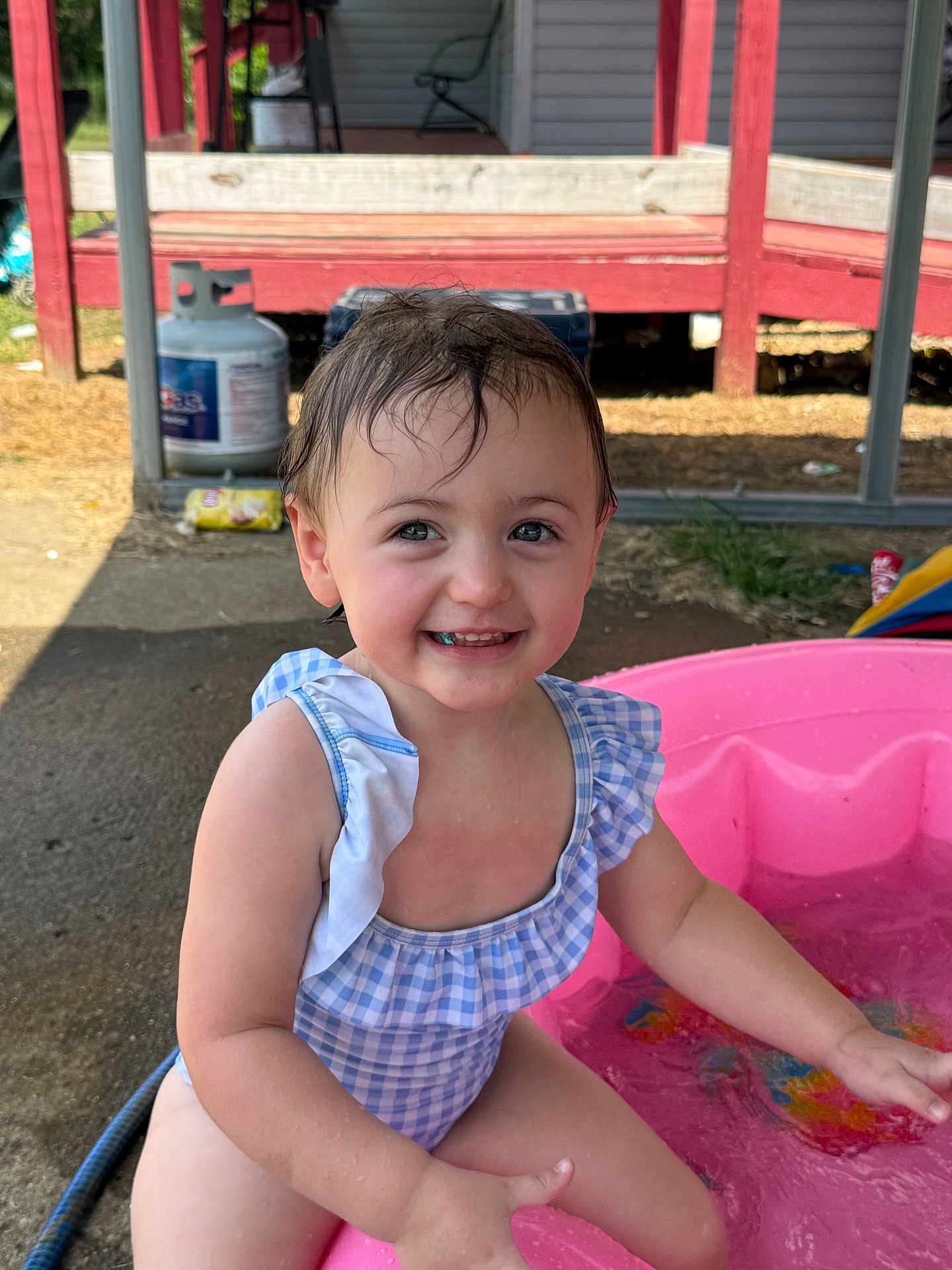 Freya joined the competition — help win amazing prizes! toddler, child, smiling, water, pool, swimsuit, outdoor, summer, happy, splashing, pink_pool, wet_hair, cute, play, sunlight, propane_tank, porch, concrete, blue, white