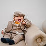 baby, child, smiling, laughing, suit, bow_tie, hat, cap, beige, couch, balloons, indoor, cute, happy, portrait, fashion, toddler, clothing, furniture, celebration
