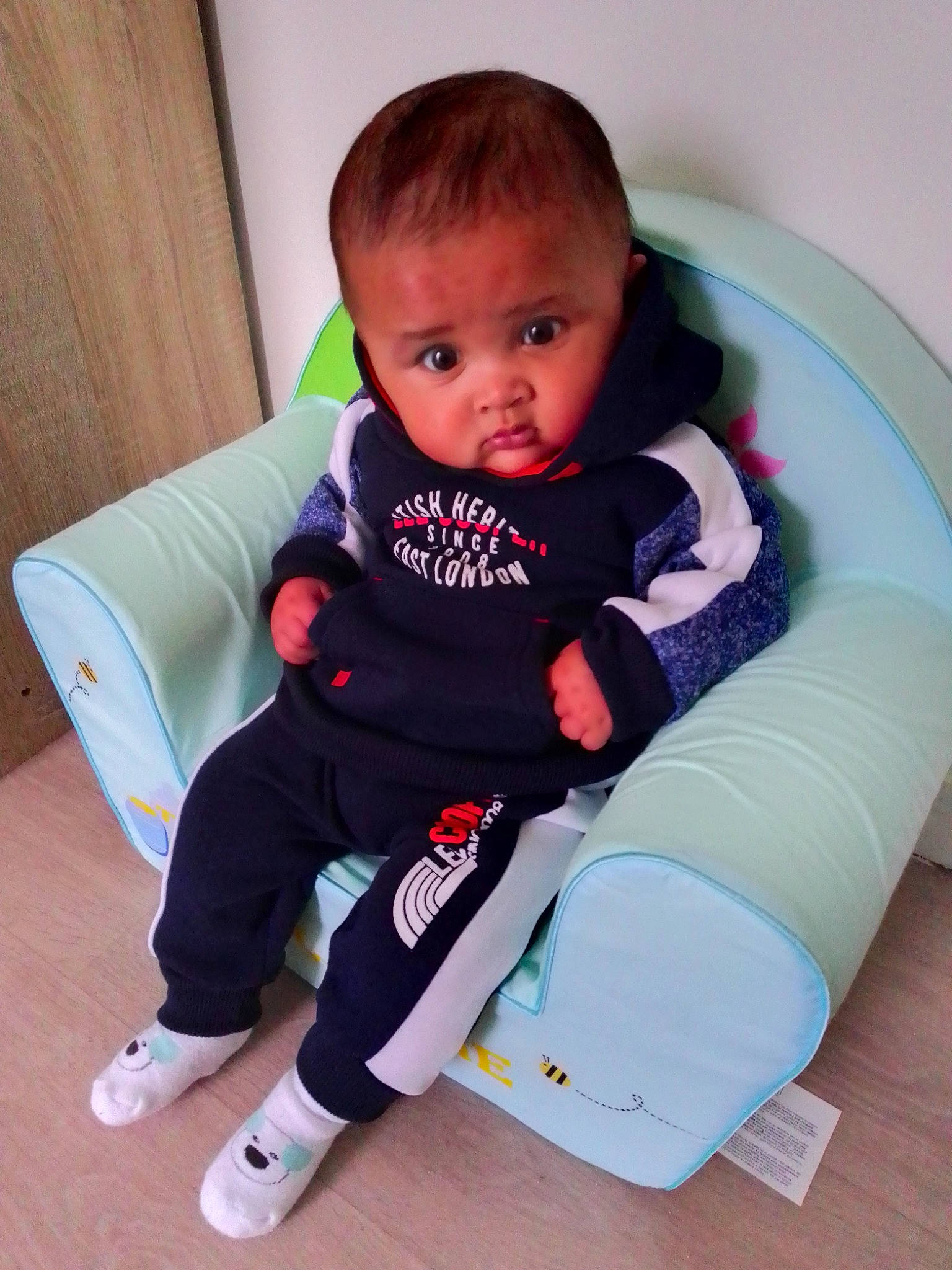 Enzo participe au concours pour gagner de l'argent avec cette photo : baby, baby_toddler_clothing, child, comfort, elbow, electric_blue, face, flooring, human_leg, knee, lap, person, room, shoe, sitting, sleeve, sneakers, sock, t_shirt, thigh