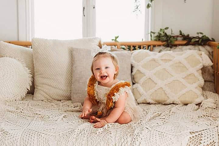 Caylee joined the competition — help win amazing prizes! bedding, child, comfort, couch, flash_photography, floor, flooring, grass, happy, hardwood, human_leg, joy, lighting, linens, living_room, person, plant, room, smile, throw_pillow