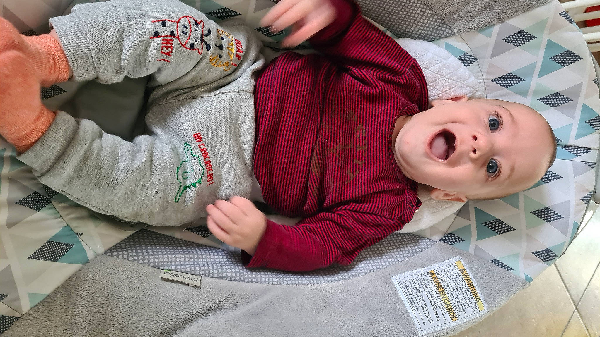 Raphaël a rejoint le concours — aidez-le/la à gagner de superbes lots ! baby, baby_products, baby_toddler_clothing, carmine, child, comfort, finger, flooring, fun, gesture, happy, linens, mouth, nail, pattern, person, plaid, room, sitting, surprise