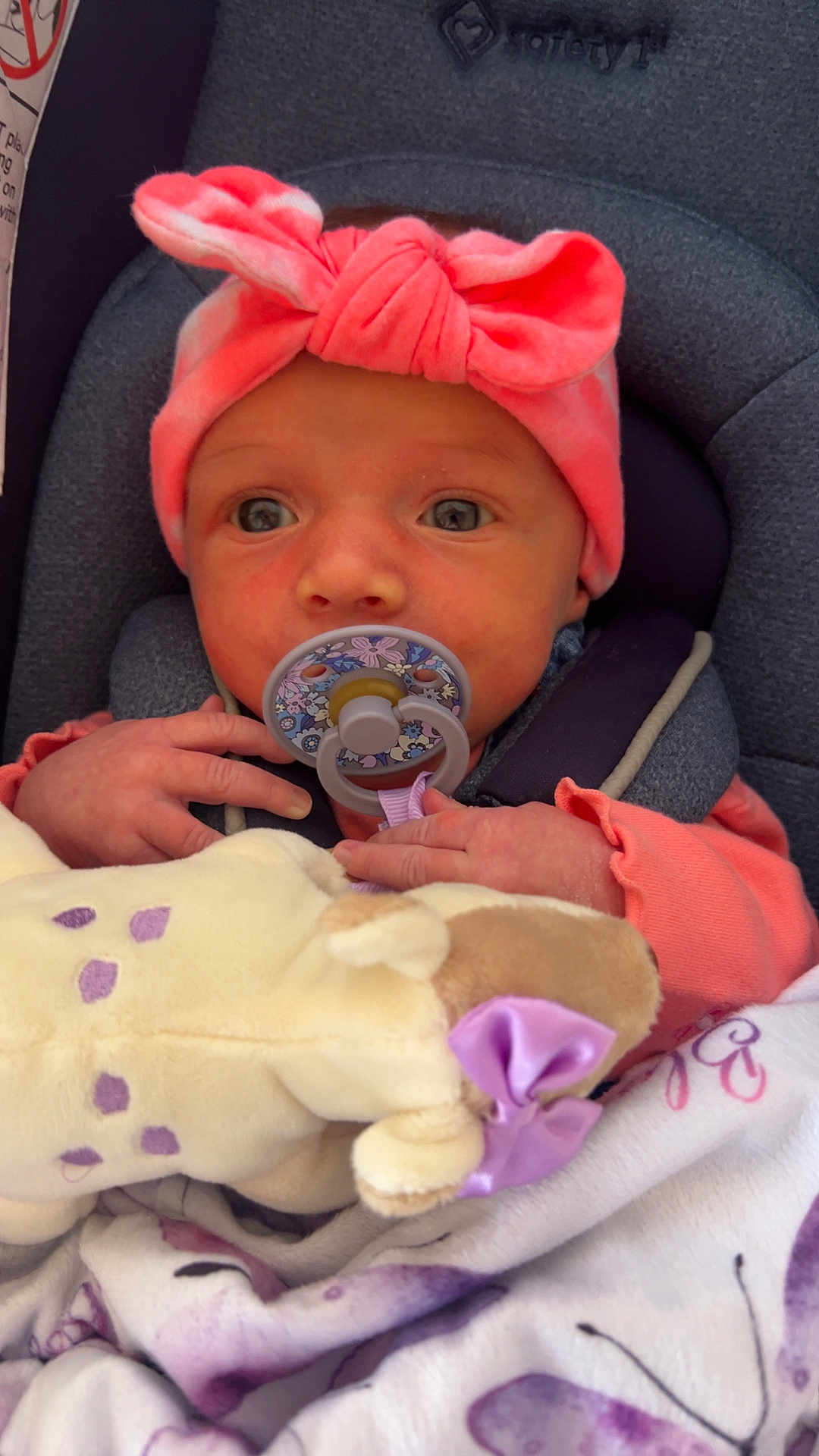 Amelia is registered to the contest to win money with this photo: baby, infant, pacifier, headband, pink, plush_toy, blanket, car_seat, child, cute, soft_toy, newborn, clothing, comfort, portrait, indoors, face, hand, expression, rest