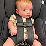baby, infant, car_seat, seatbelt, pink_bow, floral_outfit, blue_eyes, child, sitting, safety, straps, cute, young_child, indoor, portrait, close_up, serious_expression, skin, hair, hands