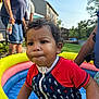 Takoah is registered to the contest to win money with this photo: toddler, child, pool, inflatable_pool, water, outdoor, summer, curly_hair, red_shirt, blue_shirt, seahorse_pattern, people, adult, backyard, grass, sunlight, daytime, person, play, fun