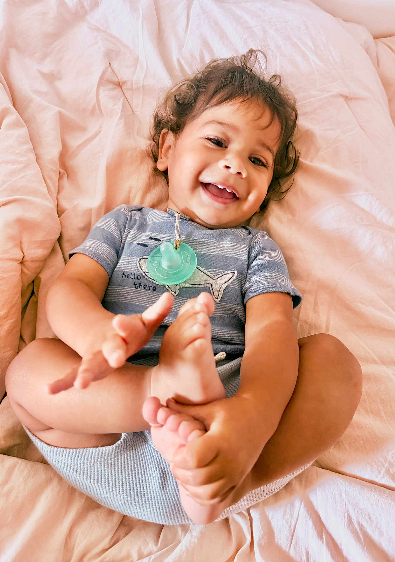 Takoah joined the competition — help win amazing prizes! baby, toddler, child, smiling, happy, feet, hands, bed, blanket, clothing, pacifier, cute, playful, portrait, indoors, soft_lighting, person, skin, infant, casual