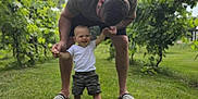 Lawson joined the competition — help win amazing prizes! adult, child, clouds, grass, greenery, holding_hands, learning_to_walk, nature, outdoor, parent, sandals, shorts, sky, smiling, summer, support, toddler, tshirt, vineyard, walking