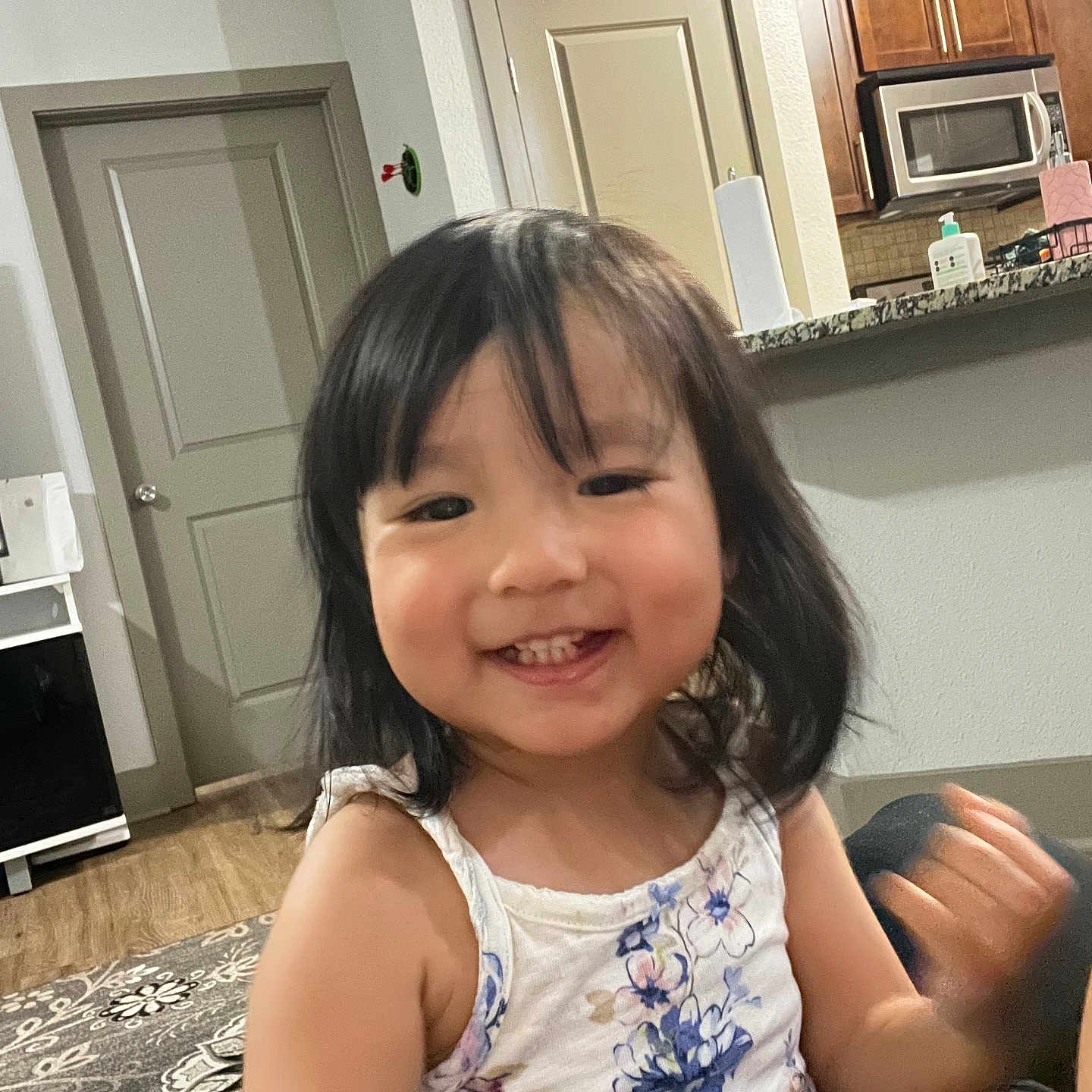 Sambodhi is registered to the contest to win money with this photo: cabinet, cheeks, child, door, face, floral, hair, happy, home, indoor, kitchen, living_room, microwave, motion_blur, person, rug, smiling, tank_top, toddler, wood_floor