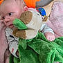baby, infant, plush_toy, green_blanket, pink_blanket, carpet, soft_toy, child, person, cute, comfort, looking_away, indoors, colorful, fabric, hand, foot, sleepwear, cozy, resting