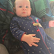Fraya joined the competition — help win amazing prizes! baby, infant, face, wide_eyes, onesie, polka_dots, navy_blue, red_trim, pacifier_clip, hand, fingers, blanket, plaid_blanket, green_blanket, couch, indoor, soft_light, portrait, lying_down, curious_expression