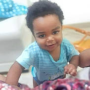 Carlos is registered to the contest to win money with this photo: baby, blue_shirt, blurred_background, casual_clothing, child, curious, cute, expression, face, furniture, hair, hand, home, indoors, person, portrait, skin, smiling, toddler, young_child