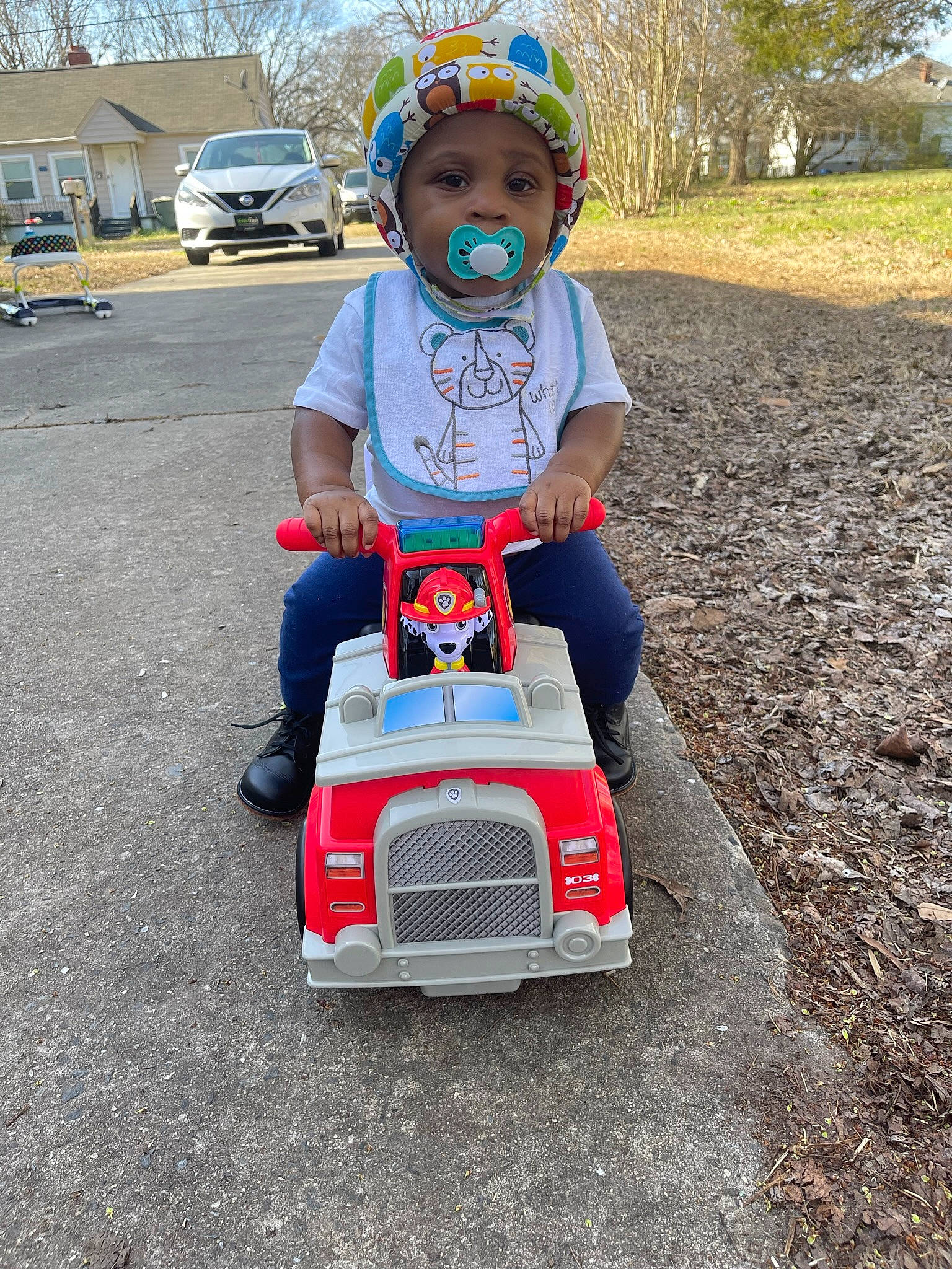 Jamari is registered to the contest to win money with this photo: asphalt, auto_part, automotive_design, automotive_exterior, automotive_tire, automotive_wheel_system, bumper, carmine, grass, headwear, helmet, motor_vehicle, person, plant, riding_toy, tire, toddler, toy, tree, vehicle