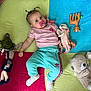Sia a rejoint le concours — aidez-le/la à gagner de superbes lots ! baby, child, pacifier, pigtails, pink_shirt, turquoise_pants, socks, toy_turtle, toy_doll, stuffed_bear, toy_horse, colorful_blanket, indoor, playtime, cute, infant, lying_down, soft_toys, curious, portrait