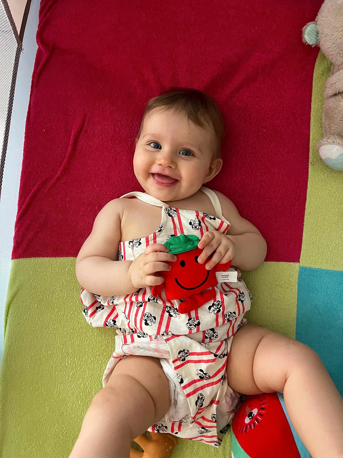 Sia participe au concours pour gagner de l'argent avec cette photo : baby, smiling, toy, plush, colorful_blanket, happy, child, cute, infant, clothing, patterned_outfit, lying_down, playtime, indoors, skin, person, hand, legs, face, joyful