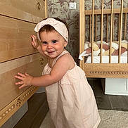 Avelina a rejoint le concours — aidez-le/la à gagner de superbes lots ! toddler, girl, child, smiling, standing, dress, headband, dresser, nursery, crib, wooden_furniture, carpet, floor, wallpaper, indoor, baby, cute, portrait, room, toy