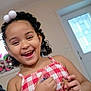Jazelle is registered to the contest to win money with this photo: child, smiling, happy, curly_hair, hair_accessories, indoor, red_and_white, checkered_pattern, top, toy, stuffed_animal, door, person, cute, playful, young, girl, holding, fun, portrait