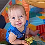 baby, child, blue_eyes, toy, dinosaur_toy, playpen, colorful, smiling, sitting, infant, cute, happy, indoor, clothing, blue_shirt, person, young_child, play, hand, face